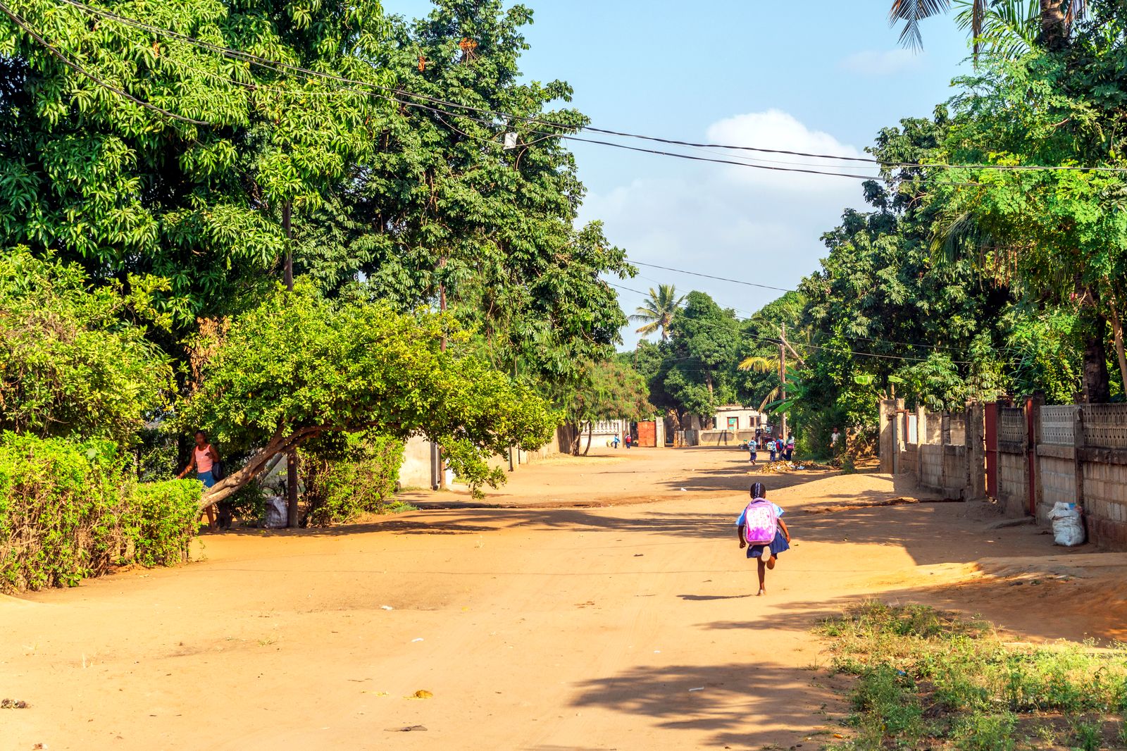 A student runs home from school along a shaded street in Moatize